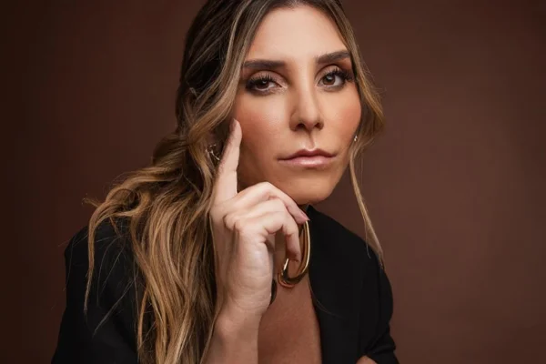 Mari Dutra posa, séria, de look preto e com o dedo no rosto - Metrópoles