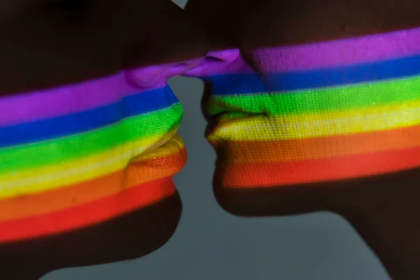 Foto colorida de pessoas preste a se beijar iluminadas por arco íris