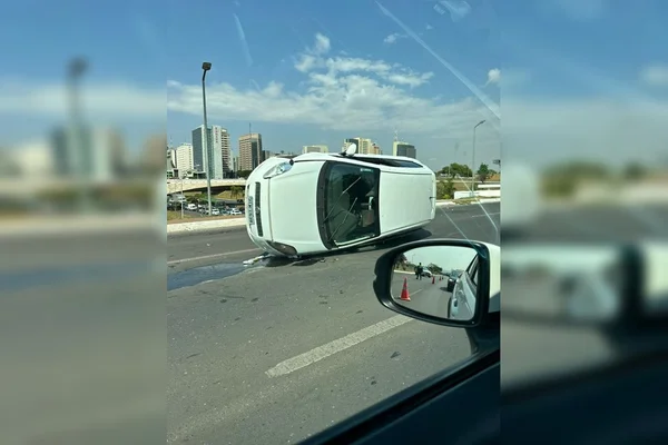 Imagem colorida mostra carro tombado em via