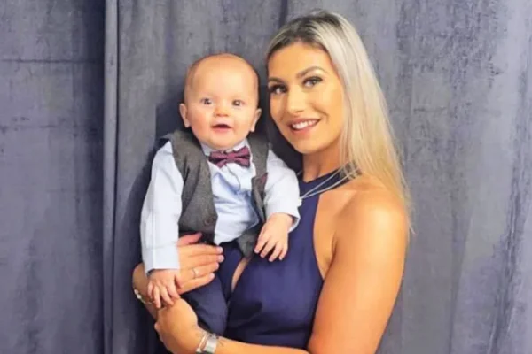 Foto colorida de uma mulher loira segurando uma criança - Metrópoles