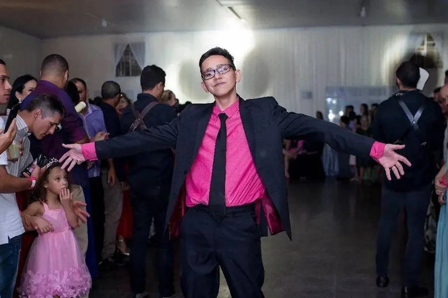 Imagem mostra jovem que foi encontrado morto em Goiás, ele usa uma camisa rosa e um terno preto. O rapaz foi encontrado já sem vida por colegas - Metrópoles