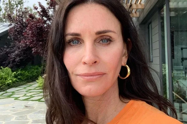 Courteney Cox de blusa laranja