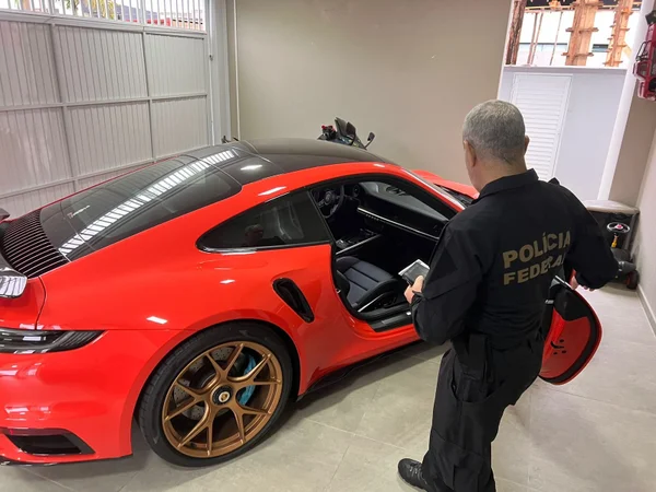 Imagem colorida de apreensões da PF em casa de homem prourado pela Interpol