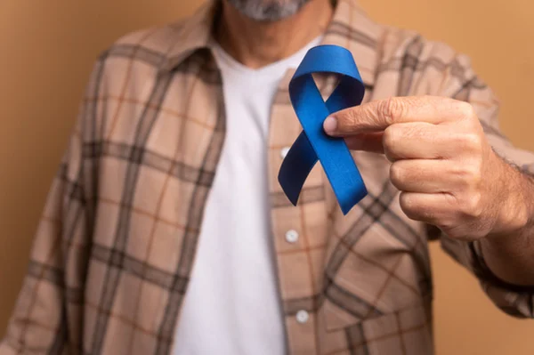 Foto colorida de homem segurando fita azul da campanha Novembro Azul, compra o câncer de próstata - Metrópoles