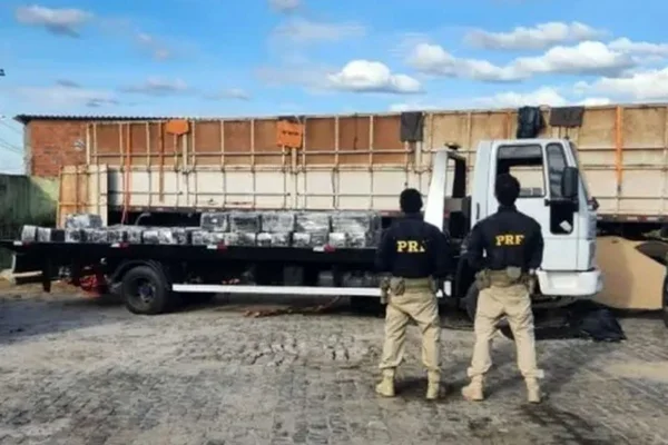 Dois agentes da PRF em frente a um caminhão