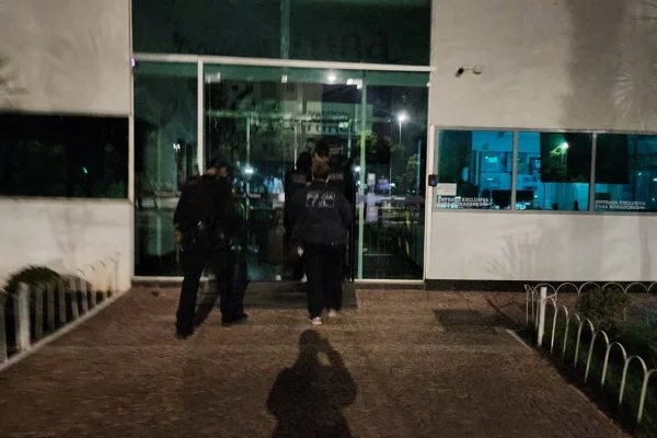 Homens caminham em direção a prédio no escuro