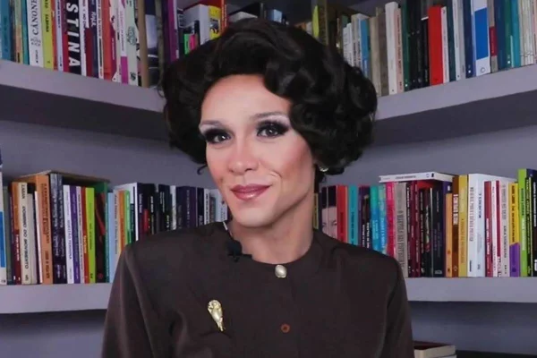 drag queen posa de blusa marrom e peruca curta - metrópoles