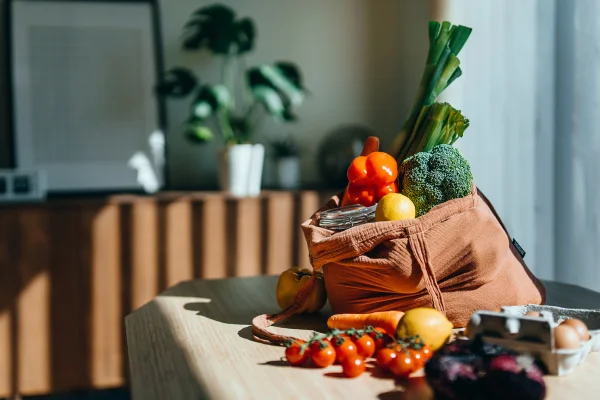 Foto colorida. A imagem mostra uma bancada na cozinha com um saco cheio de legumes - Metrópoles
