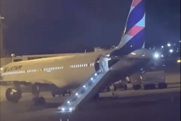 Imagem colorida mostra avião no aeroporto de Guarulhos com a escada inflável acionada após homem tentar abrir porta traseira do avião - Metrópoles