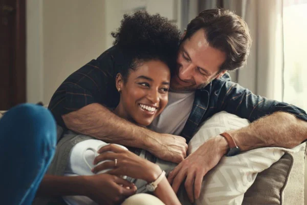 Casal se abraçando sorrindo no sofá