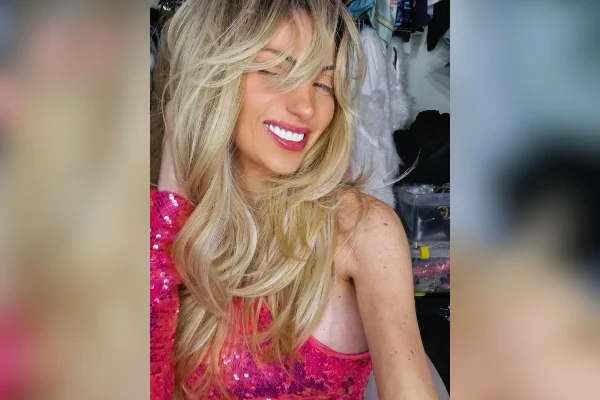 Imagem colorida de mulher loira vestida de roupa rosa. Metrópoles