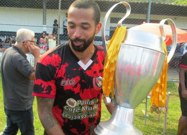 foto em pb de jogador da várzea com a taça na mão - Metropoles
