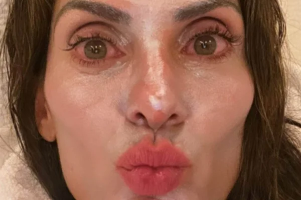 Mulher branca tirando uma selfie com close em seu rosto. Usando um creme branco na pele, ela tem os olhos verdes e mostra como eles estão brancos devido à água do mar