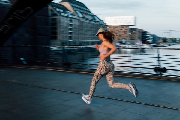 Imagem mostra mulher com roupa estampada e boné praticando corrida na rua - Metrópoles