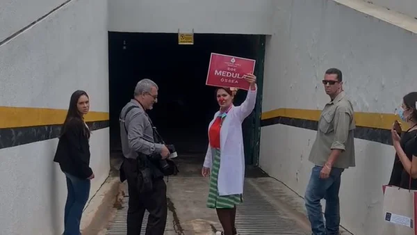 Vestida de palhaço, Michelle Bolsonaro segura cartaz defendendo doação de medula óssea