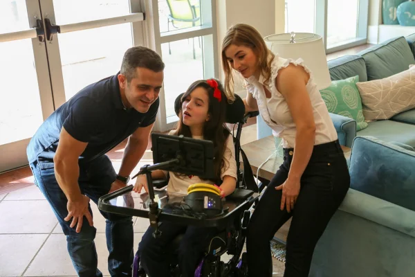 Família reunida enquanto filha utiliza plataforma de comunicação assistiva