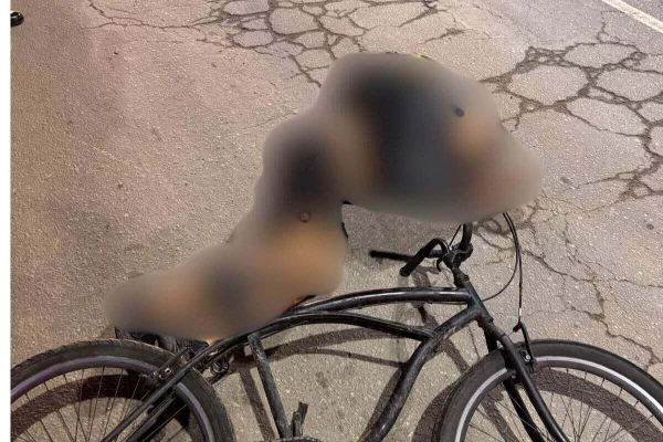 Jovem caído em asfalto, com roupa preta, ao lado de bicicleta caída - Metrópoles