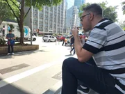 Idoso se protege do sol com jornal em trecho da Avenida Paulista