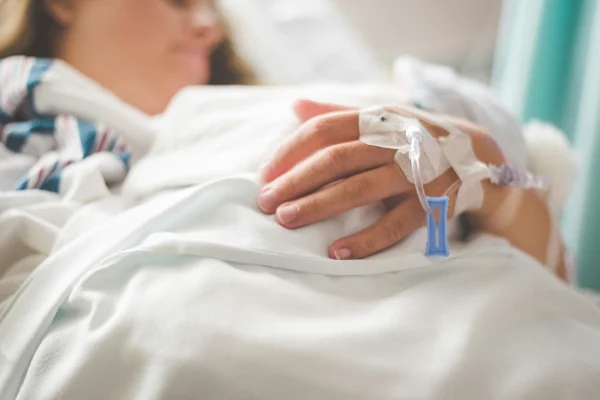 Imagem mostra mulher internada no hospital, com um acesso na mão - Metrópoles