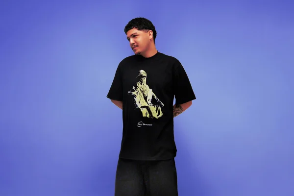 Na imagem com cor, homem veste camisa preta com estampa em fundo roxo - Metrópoles
