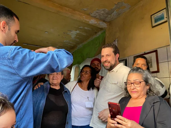 Imagem colorida mostra Guilherme Boulos tirando foto com apoiadores - Metrópoles