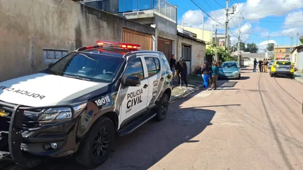 carro da polícia estacionado em frente a uma casa e pessoas na rua