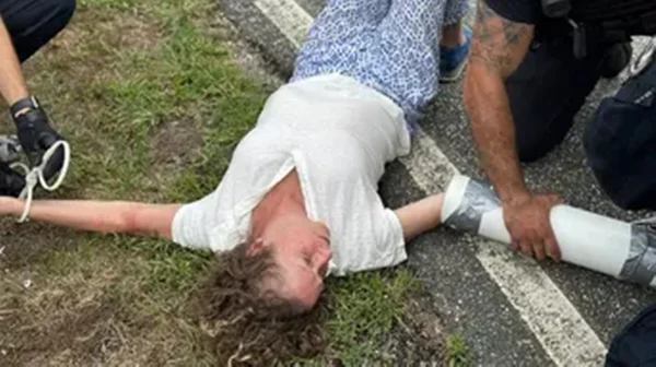 Imagem colorida de Abigail Disney deitada no chão com os braços conectados a canos - Metrópoles