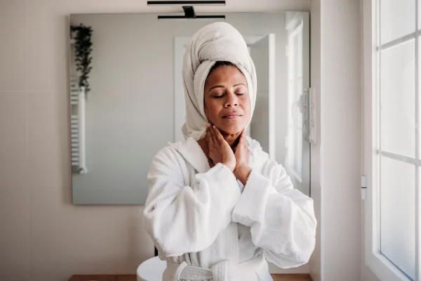 Foto de mulher madura sorridente massageando o rosto no banheiro de casa. praticando autocuidado