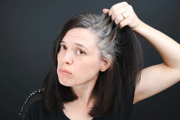 mulher de cabelo preto mostrando os fios brancos