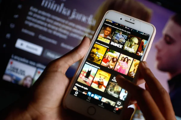 celular com catalogo de aplicativo e filme ao fundo - metrópoles