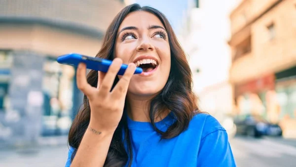 Mulher com blusa azul falando ao telefone