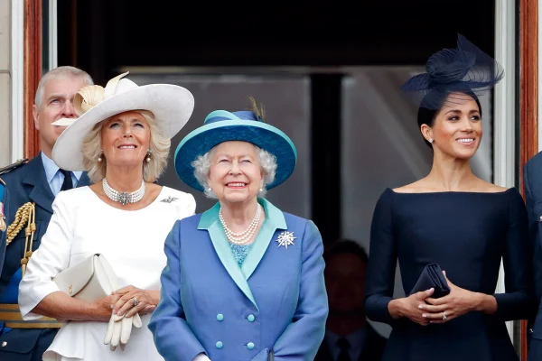 Foto colorida. Camilla Parker, rainha Elizabeth e Meghan Markle na varanda do Palácio de Buckingham