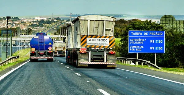 três caminhões trafegam em rodovia brasileira