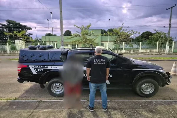 Imagem colorida, uma viatura da Polícia Civil, um agente da corporação e um preso - Metrópoles