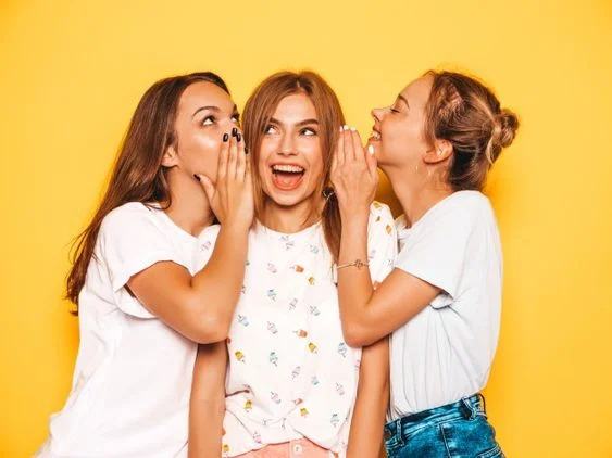 amigas fofocando, fundo amarelo, garotas de blusa branca - metrópoles
