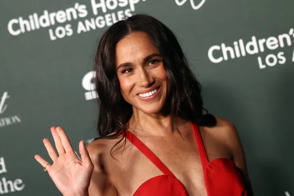 Foto colorida de mulher com vestido vermelho e acenando - Metrópoles