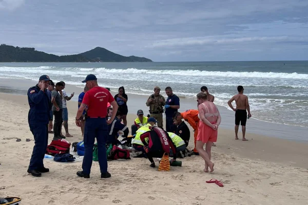 Foto mostra grupo de pessoas se reunindo ao redor de homem afogado em praia de Bombinhas, em Santa Catarina