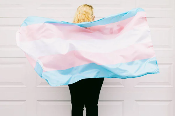 Mulher de costas segura bandeira trans - Metrópoles