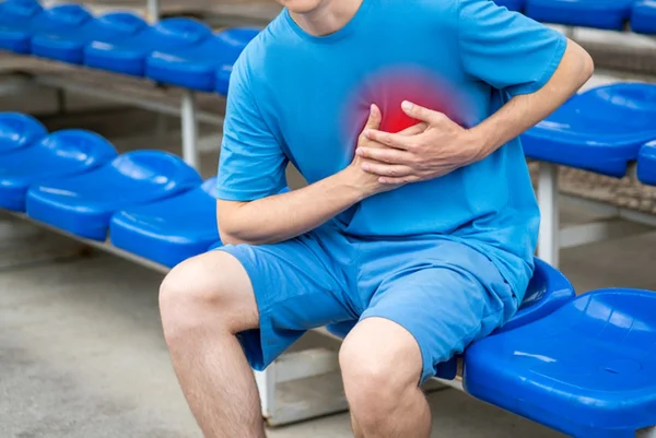 Atleta sentado em arquibancada com mão no peito - morte súbita - antidepressivo