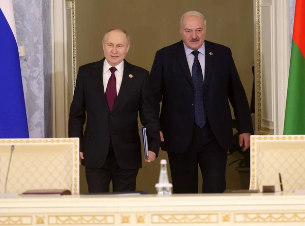 Imagem colorida mostra Putin e Lukashenko andando com as bandeiras da Rússia e Belarus ao lado - Metrópoles