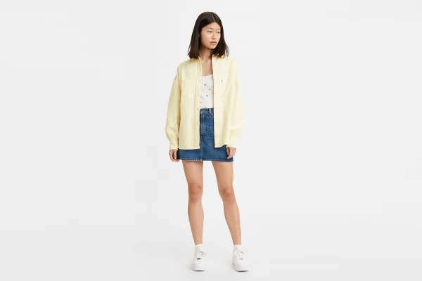 Modelo asiática com jaqueta bege, saia jeans e blusa branca