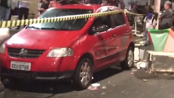 Carro vermelho parado após colidir com uma barraca. A área esta isolada e conta com pessoas observando a volta; motorista do veículo teve um mal súbito e atropelou seis pessoas - Metrópoles
