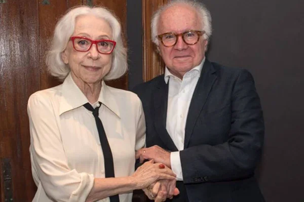 foto colorida de Fernanda Montenegro e Joaquim Falcão de mãos dadas - metrópoles