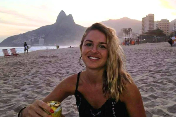 Imagem colorida de mulher loira identificada como a jornalista Charlotte Peet em praia do Rio de Janeiro