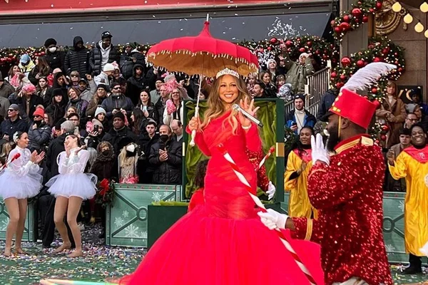 Mariah Carey de vestido vermelho segurando sombrinha e microfone