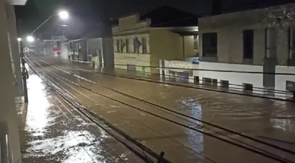 Imagem colorida de uma rua alagada, com água que chega a altura das casas - Metrópoles