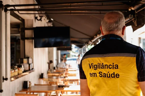 Imagem colorida mostra agente de Vigilância em Saúde durante fiscalização sobre bebidas com metanol. Metrópoles
