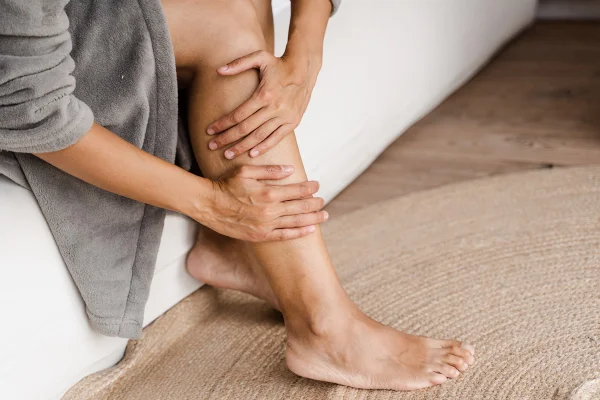 Trombose venosa profunda e varizes de mulher africana. Menina tocando as pernas e olhando para as veias. Procedimento de escleroterapia no médico cirurgião vascular visitante