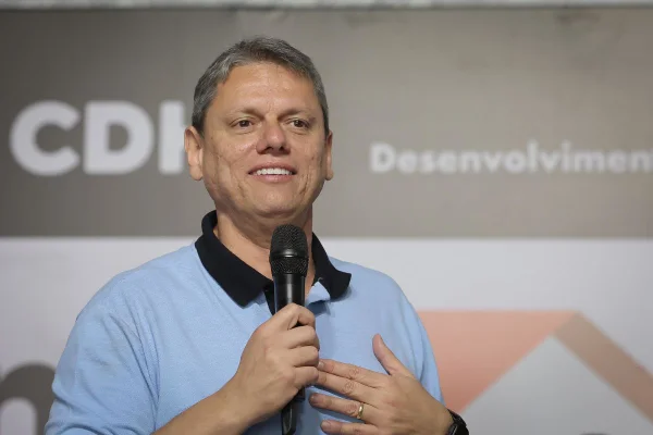 Imagem colorida mostra governador de São Paulo, Tarcísio de Freitas, sorrindo com os dentes à mostra. Ele é um homem branco com cabelos grisalhos e veste camisa azul claro com gola polo azul marinho - Metrópoles