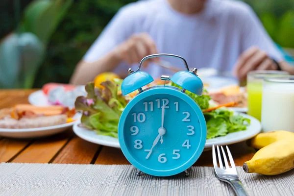 Foto colorida de prato de salada e relógio azul - Metrópoles